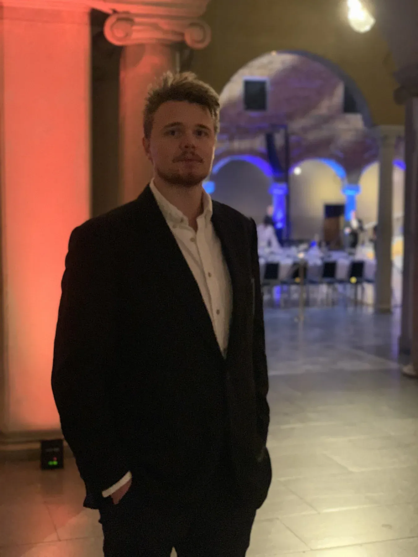 David in a dark suit in a grand hall