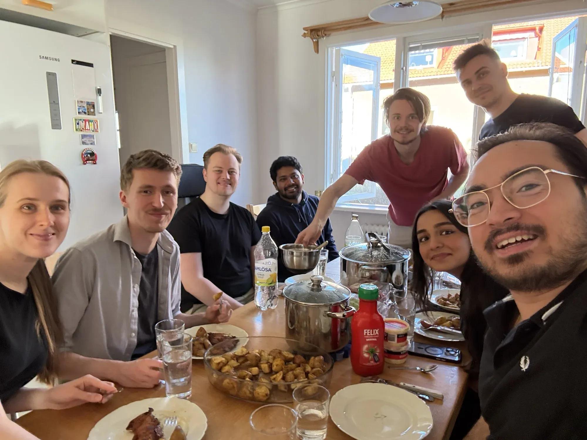 The team round a kitchen table, mid-dinner