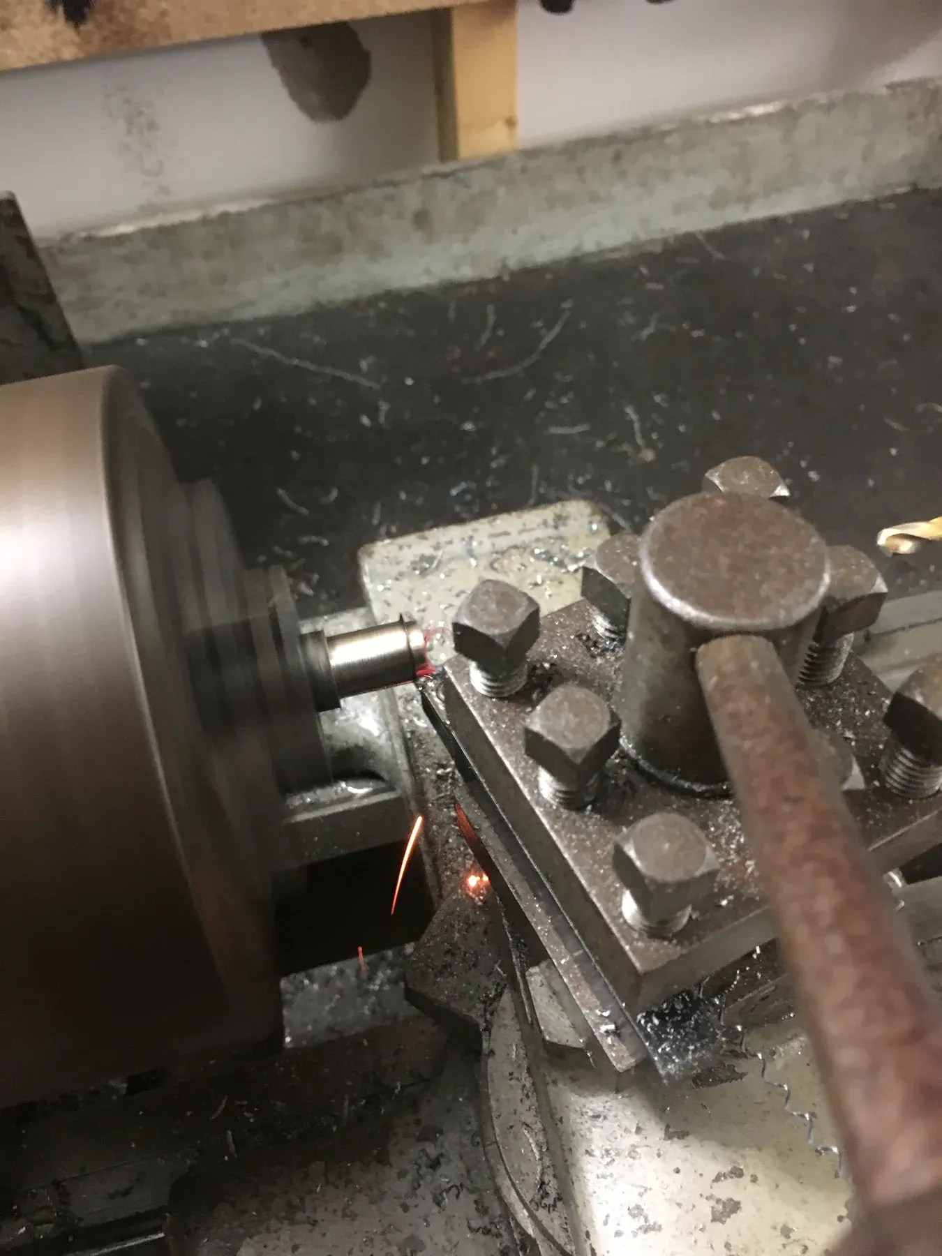 An old metal lathe cutting a part in the garage