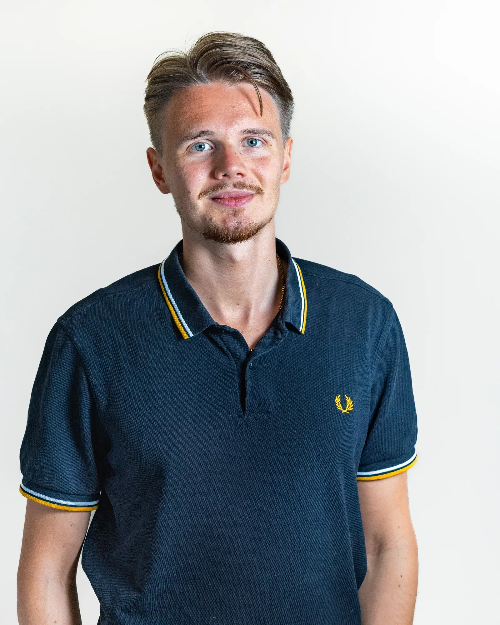 David Bacelj in a navy polo shirt against a white wall